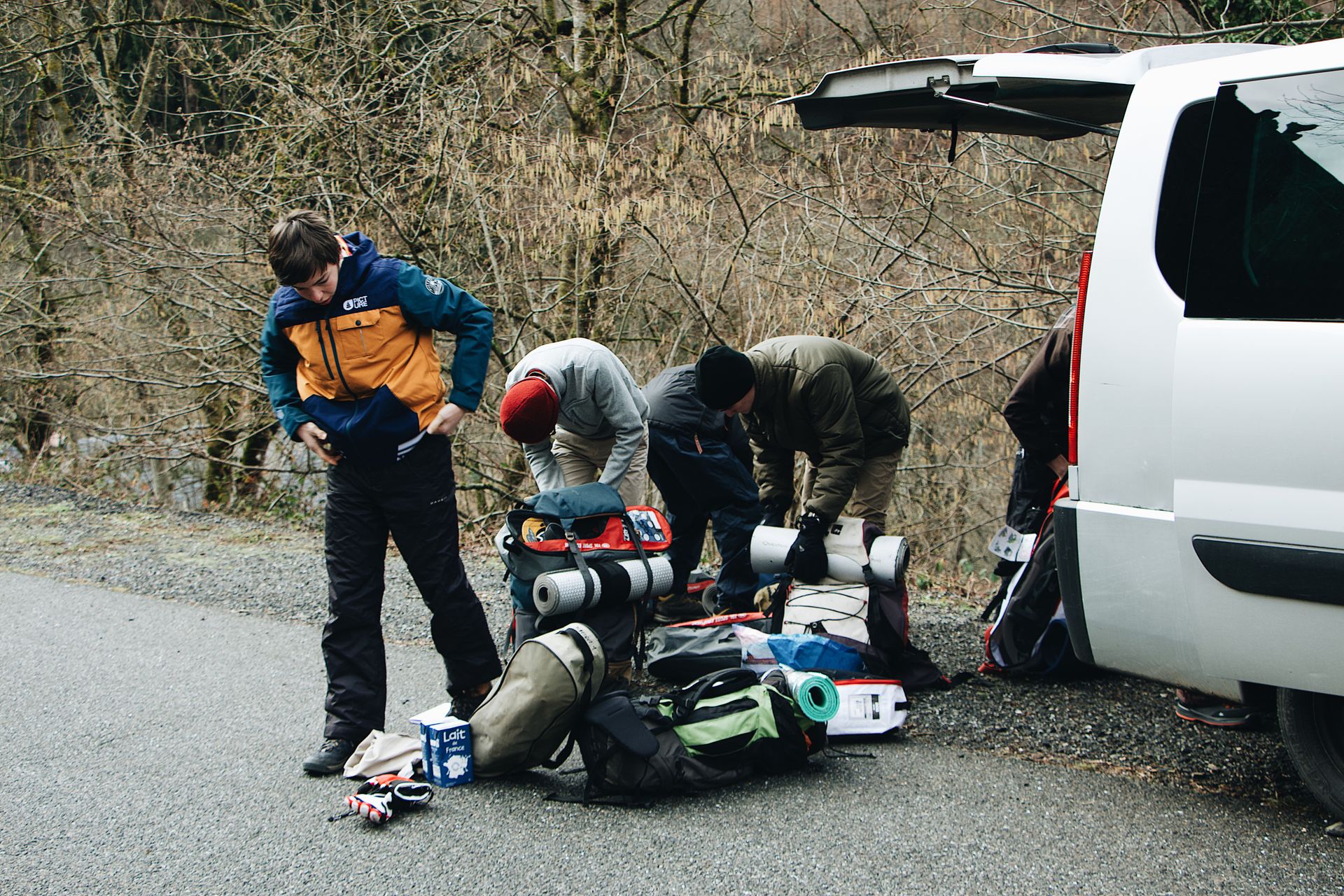 A guided adventure group taking a break and checking their equipment next to a support vehicle.